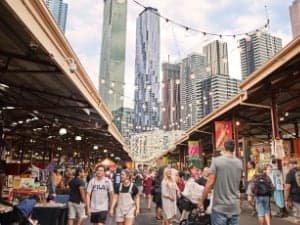 Image of a crowded open air market with skyscrapers in thebackground