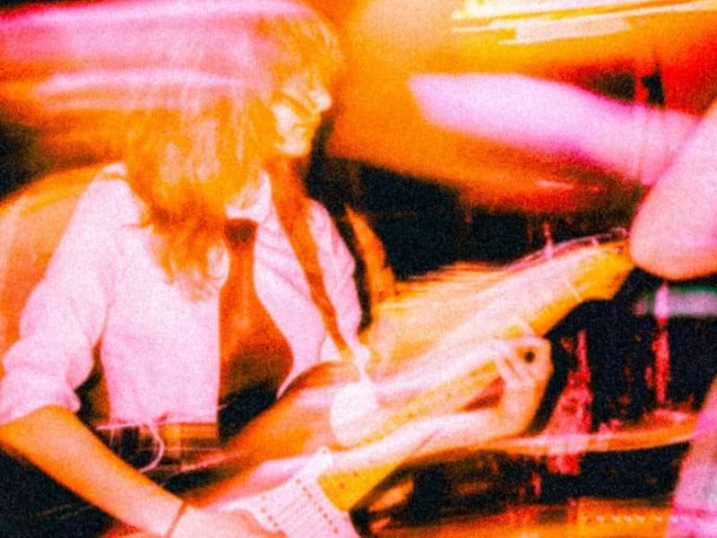 Blurred photo of a musician with long hair and an electric guitar