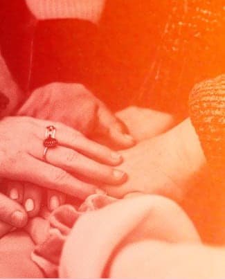 Photo of hands taken as people stand in a circle and take turns to put their hand in the centre, then raise up their hands while shouting a cheer, usually performed by a group before an action is taken
